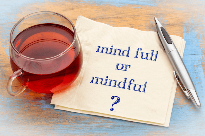 cup of tea and napkin that says mind full or mindful with a pen on a blue and brown wood background